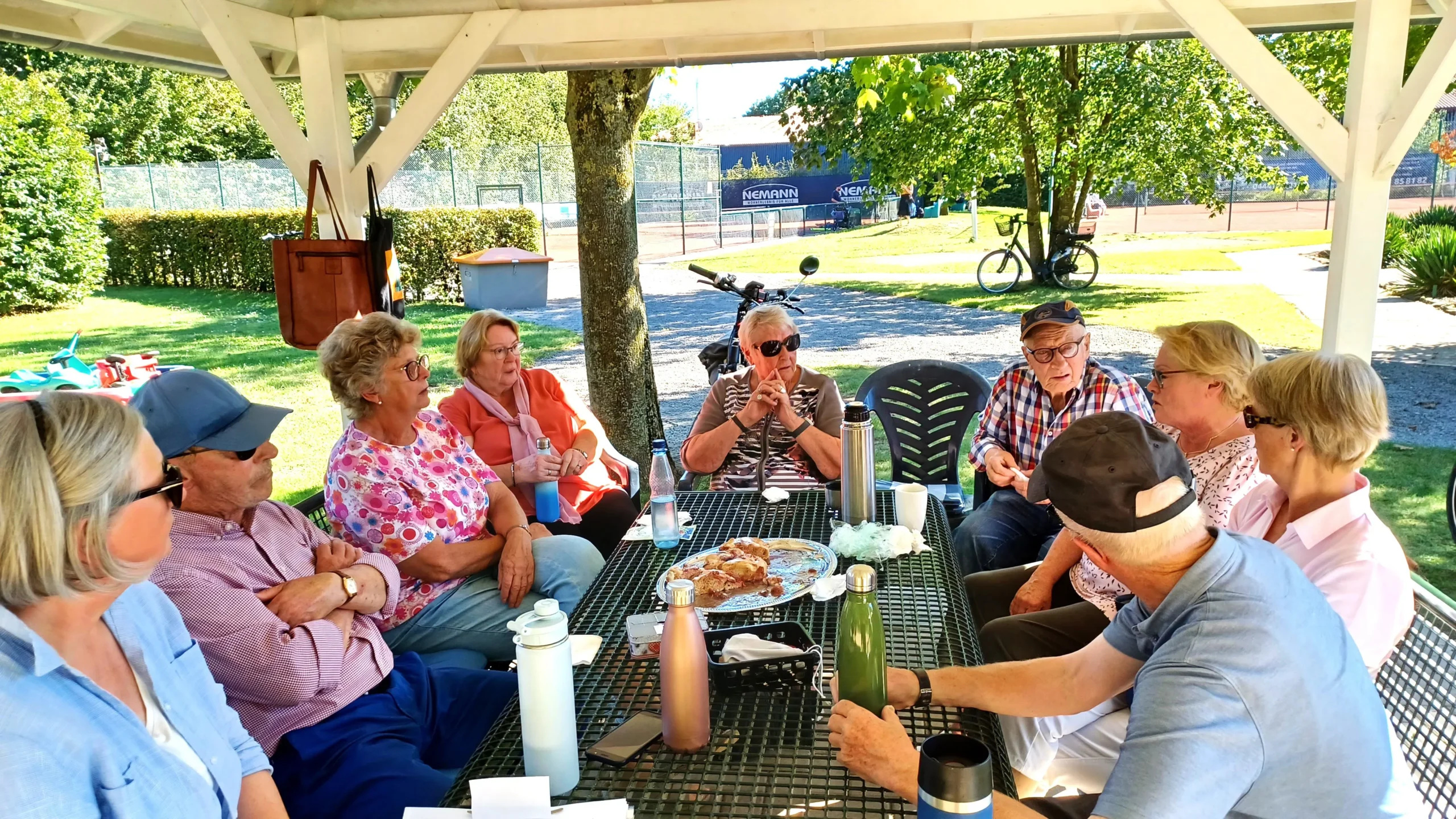 Unter dem Pavillon sitzt eine Gruppe und picknickt